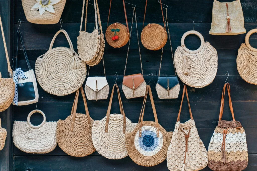 Handcrafted rattan and straw bags displayed on a wall